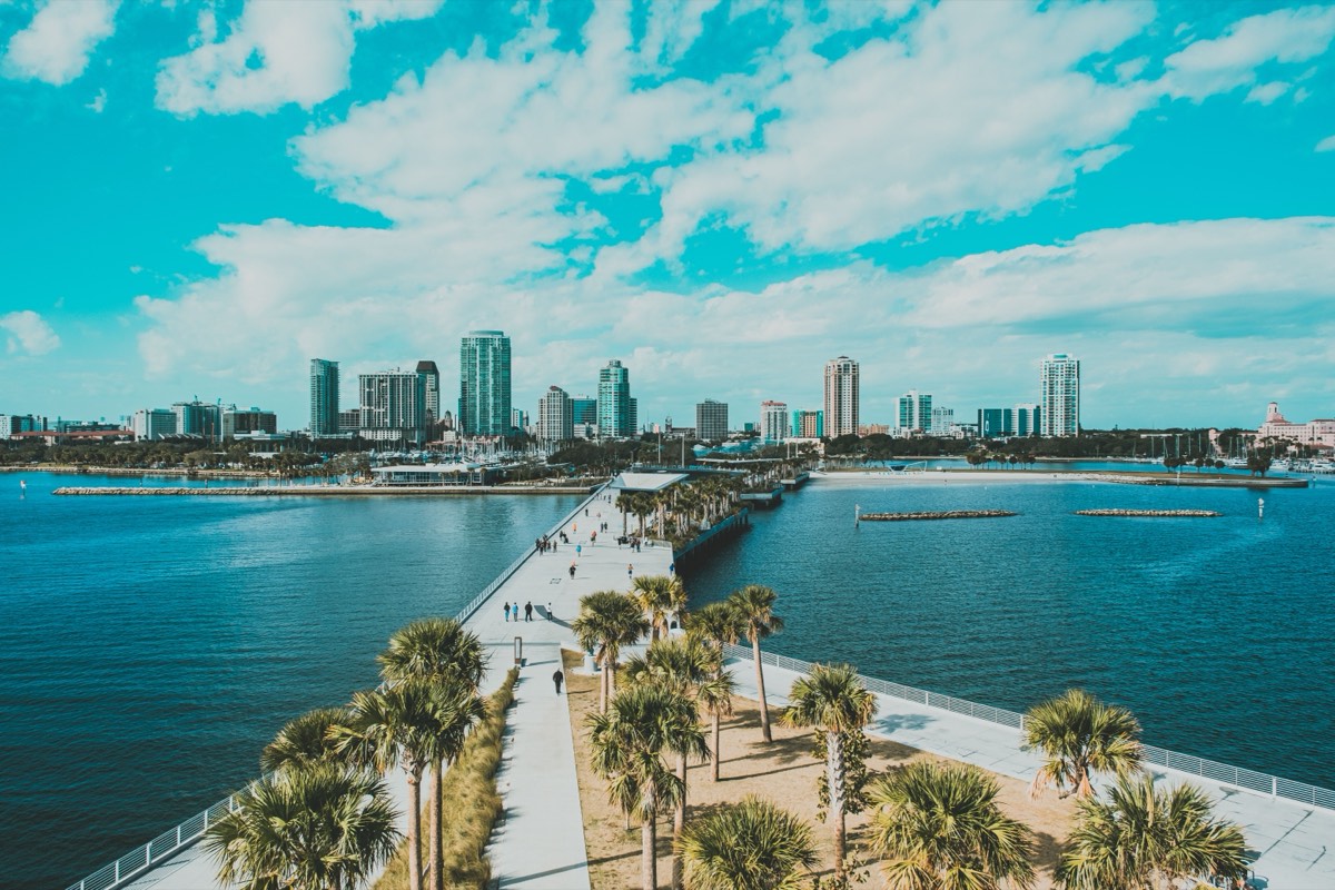 View down the St. Pete Pier toward the downtown St. Petersburg skyline, with palm trees and the turquoise waters of Tampa Bay